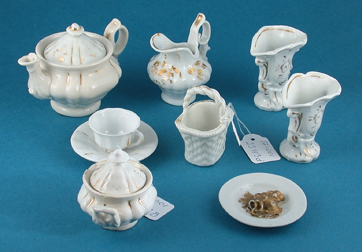 Ofärgad glasyr med obränd gulddekor.
:1 Kaffekanna med lock, H 65 mm.
:2 Sockerskål med lock, H 60 mm.
:3 Gräddkanna, H 55 mm.
:4 Korg, H 60 mm.
:5 Kaffekopp med fat, H 25 mm.
:6 Fat (med druvklase i relief) Diam 60 mm.
:7 Vas, H 60 mm.
:8 Vas, H 60 mm.