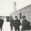 Tre män utanför tegelbyggnad, Intendenturfältövning Tällberg, mars 1962.