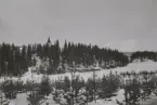 Kuperad terräng med kyrka på höjd, vinterfältövning 1960-tal.