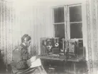 Radiotelegrafist med hörlurarvid anläggning inomhus.