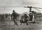 Två soldater lämnar springande Alouette-helikopter.