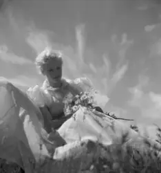 Leende blond kvinna med sommarklänning och blomsterbukett, m