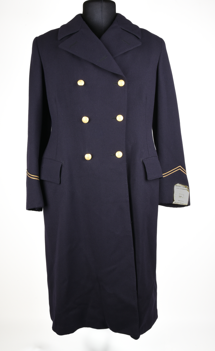 Rock av blått ylle, med sidenfoder. Dubbelknäppt med åtta knappar i gulmetall. Knapparna med krönt vinghjul tillhör 1909 års uniformsreglemente. Framtill två fickor med lock i midjehöjd. Två innerfickor i brösthöjd. Vid kragen en hank för upphängning av kavajen. Baktill sprund och slejf med två knappar. Gradbeteckning för kontorist vid ärmarna. 
Vid vänstra ärm, etikett med text: 
"FÖRSVARETS FABRIKSVERK 
Centrala beklädnadsverkstaden
Order: 23074
Verk: S.J. 24 ts.
Namn: Lindsén 18/4
Adress: Sthlm-Norra
egna galoner lämnade
Grad: Knt.
Tyg nr:
Utförande: Sidenfoder
Mått: 117-64½
Lev. tid:
Anm.:"