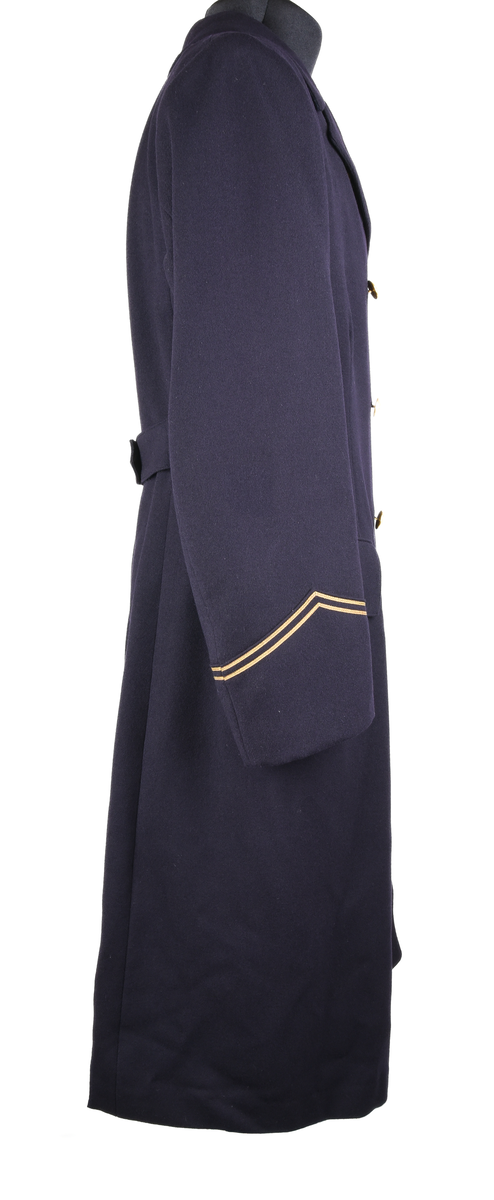 Rock av blått ylle, med sidenfoder. Dubbelknäppt med åtta knappar i gulmetall. Knapparna med krönt vinghjul tillhör 1909 års uniformsreglemente. Framtill två fickor med lock i midjehöjd. Två innerfickor i brösthöjd. Vid kragen en hank för upphängning av kavajen. Baktill sprund och slejf med två knappar. Gradbeteckning för kontorist vid ärmarna. 
Vid vänstra ärm, etikett med text: 
"FÖRSVARETS FABRIKSVERK 
Centrala beklädnadsverkstaden
Order: 23074
Verk: S.J. 24 ts.
Namn: Lindsén 18/4
Adress: Sthlm-Norra
egna galoner lämnade
Grad: Knt.
Tyg nr:
Utförande: Sidenfoder
Mått: 117-64½
Lev. tid:
Anm.:"