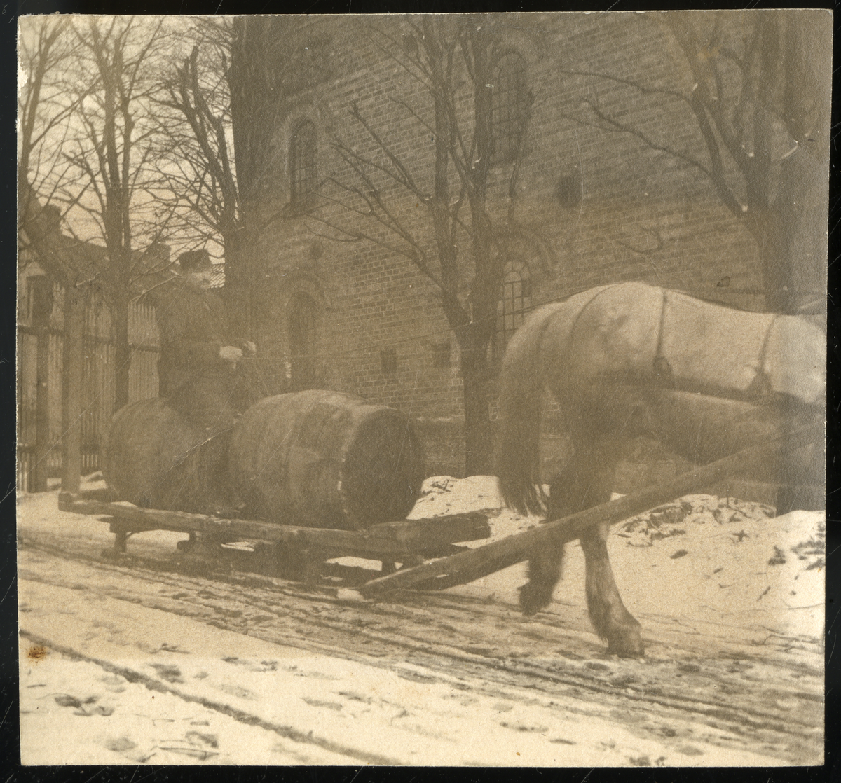 Foto av formann på Lundetangen bryggeri Karl Halvorsen (1853 - 1933) sittende på øltønner som blir slept av hest. Bryggeriet er murbygget som sees i bakgrunnen

Foto nr. 4 er retusjert av fotoarkivar

Påskrift bak foto:

Karl Halvorsen Goberg kjørte
på Lundetangen bryggeri
Var stallmester