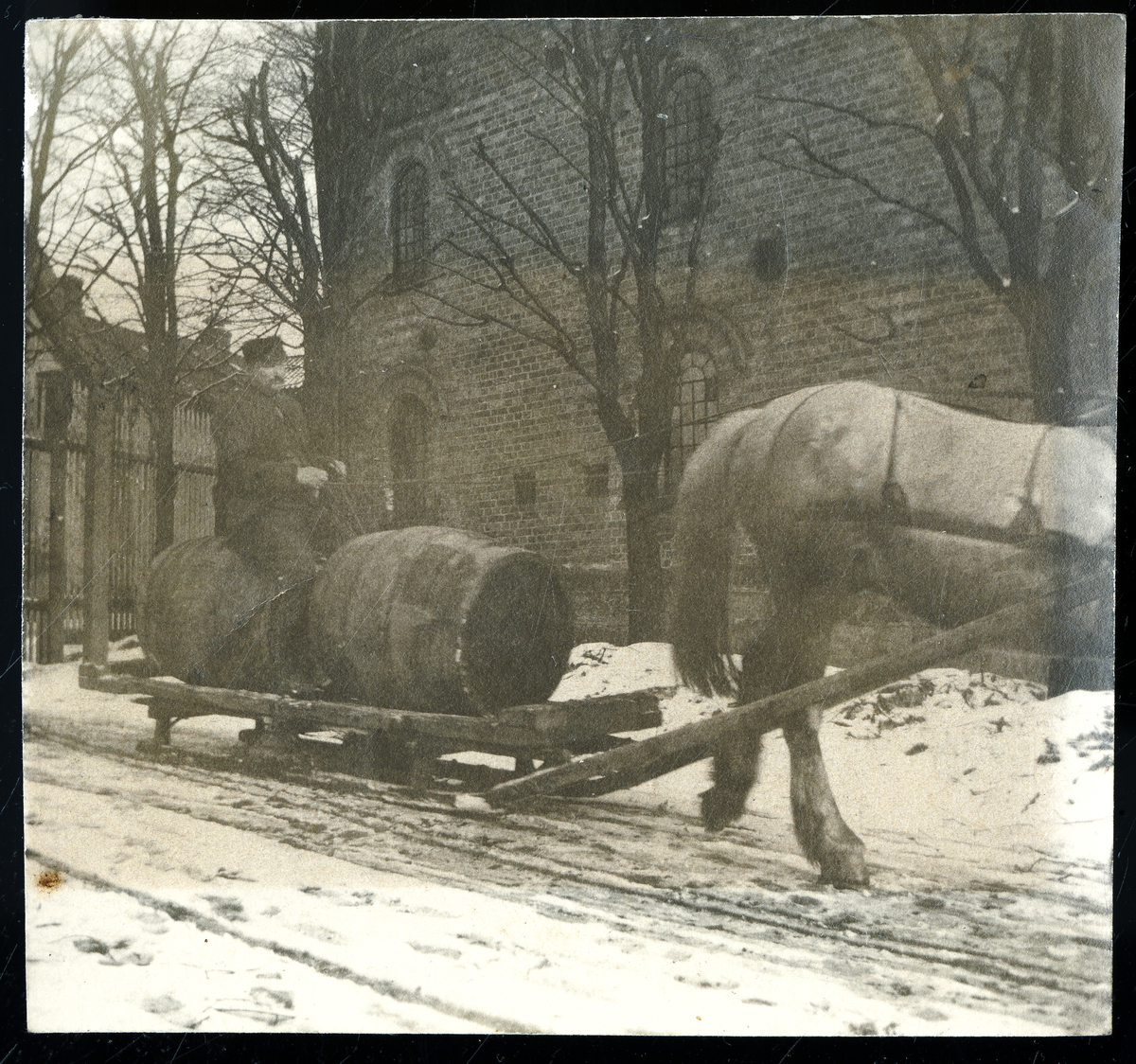 Foto av formann på Lundetangen bryggeri Karl Halvorsen (1853 - 1933) sittende på øltønner som blir slept av hest. Bryggeriet er murbygget som sees i bakgrunnen

Foto nr. 4 er retusjert av fotoarkivar

Påskrift bak foto:

Karl Halvorsen Goberg kjørte
på Lundetangen bryggeri
Var stallmester