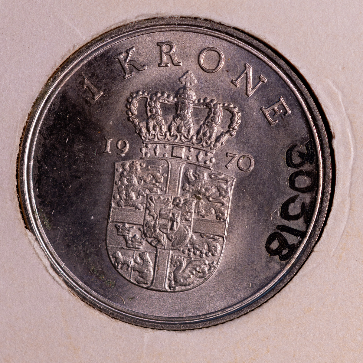 Danskt mynt, av kopparnickel. 1 krone, präglingsår 1970Åtsida: Högervänd profil av konungen samt texten: "FREDERIK IX KONGE AF DANMARK".Frånsida: Präglingsår, valör, det danska riksvapnet. 