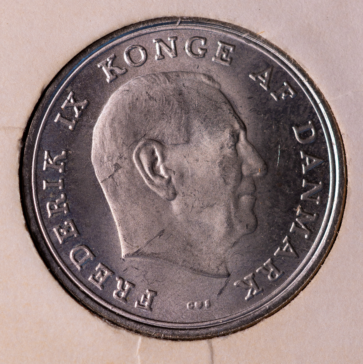 Danskt mynt, av kopparnickel. 1 krone, präglingsår 1970Åtsida: Högervänd profil av konungen samt texten: "FREDERIK IX KONGE AF DANMARK".Frånsida: Präglingsår, valör, det danska riksvapnet. 