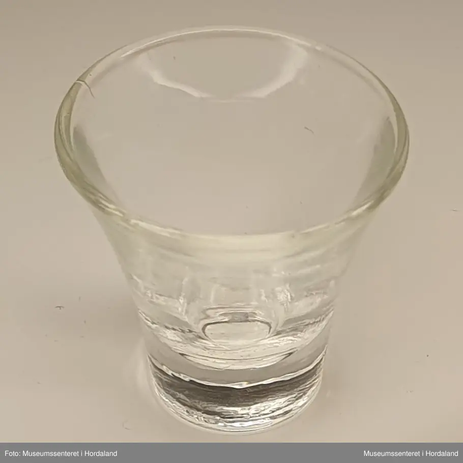 Lite glassbeger med konisk form.

