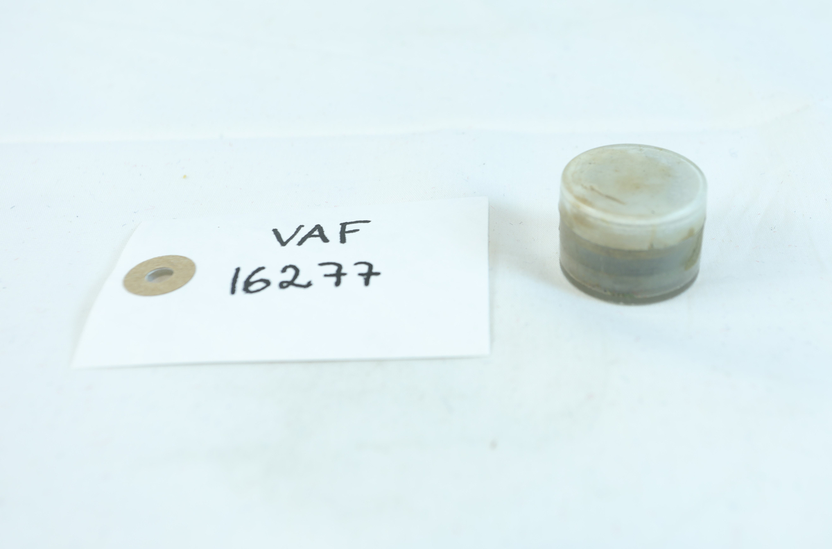 Rund liten boks i plast til oppbevaring av 7 sirkelformede metallringer. Trolig utstyr til verktøy.