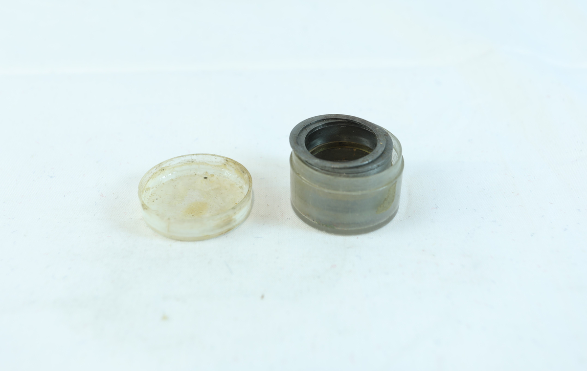 Rund liten boks i plast til oppbevaring av 7 sirkelformede metallringer. Trolig utstyr til verktøy.