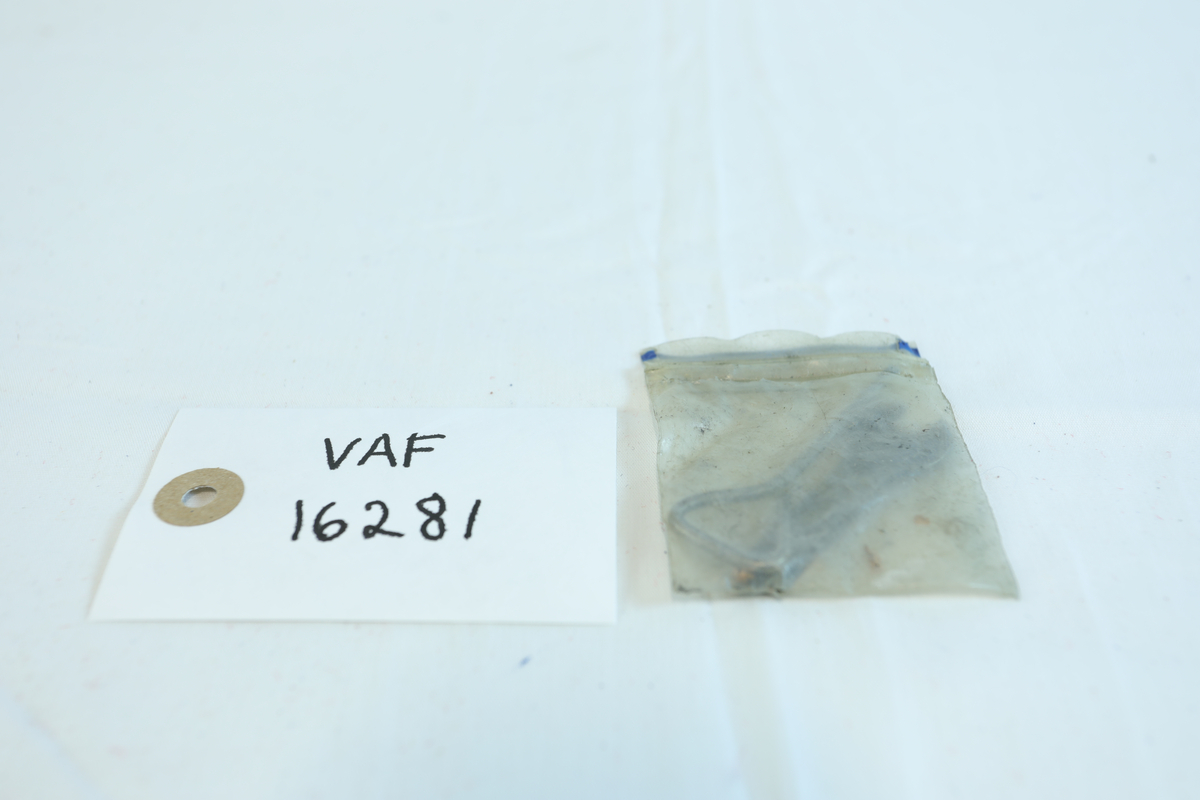 Liten plast pose, minigrip-pose, med tre redskaper i metall. Det er to fastnøkler i mørkt metall. Det siste verktøyet er sølvfarget/rustfritt stål. Den har et triangel-håndtak og tilspisset bunn. 