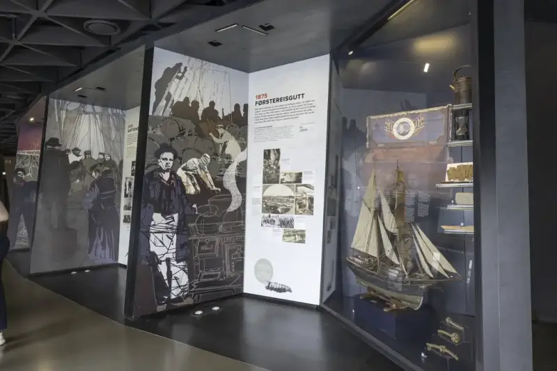 Exhibition wall with illustrations, text, and maritime objects in the At Sea! exhibition at the Norwegian Maritime Museum.