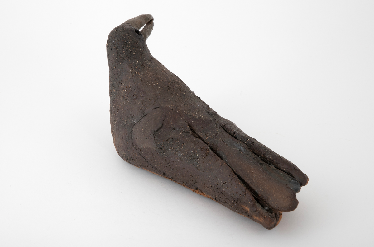 Keramikkskulptur forestillende en hvilende måke. Skulpturen er laget av utkjevlet leire som er bøyd sammen og formet. Ujevn overflate med antydning til sprekkdannelser. Grovt gods dekket med mørkebrun, matt glasur. Blank, grønnlig glasur på nebb og enkelte steder på kroppen. Måkens vinger er antydet ved rissing i godset.
