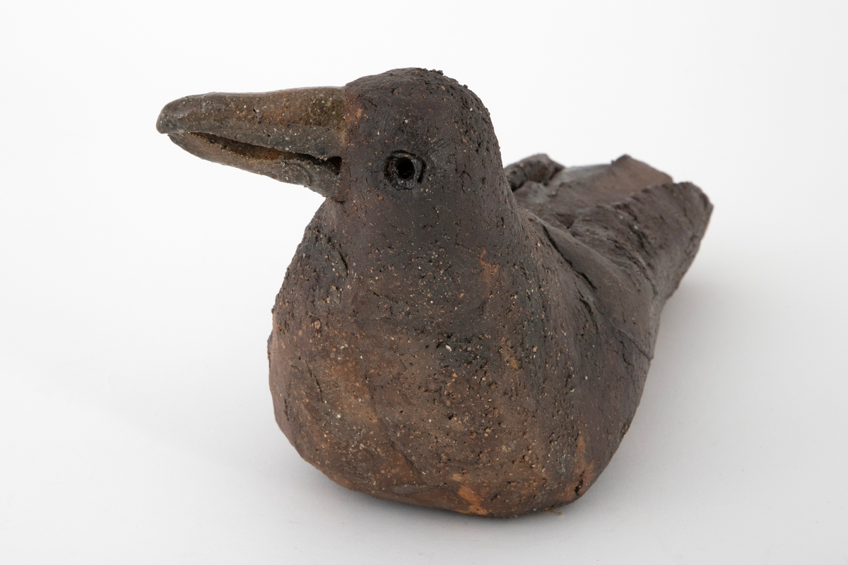 Keramikkskulptur forestillende en hvilende måke. Skulpturen er laget av utkjevlet leire som er bøyd sammen og formet. Ujevn overflate med antydning til sprekkdannelser. Grovt gods dekket med mørkebrun, matt glasur. Blank, grønnlig glasur på nebb og enkelte steder på kroppen. Måkens vinger er antydet ved rissing i godset.