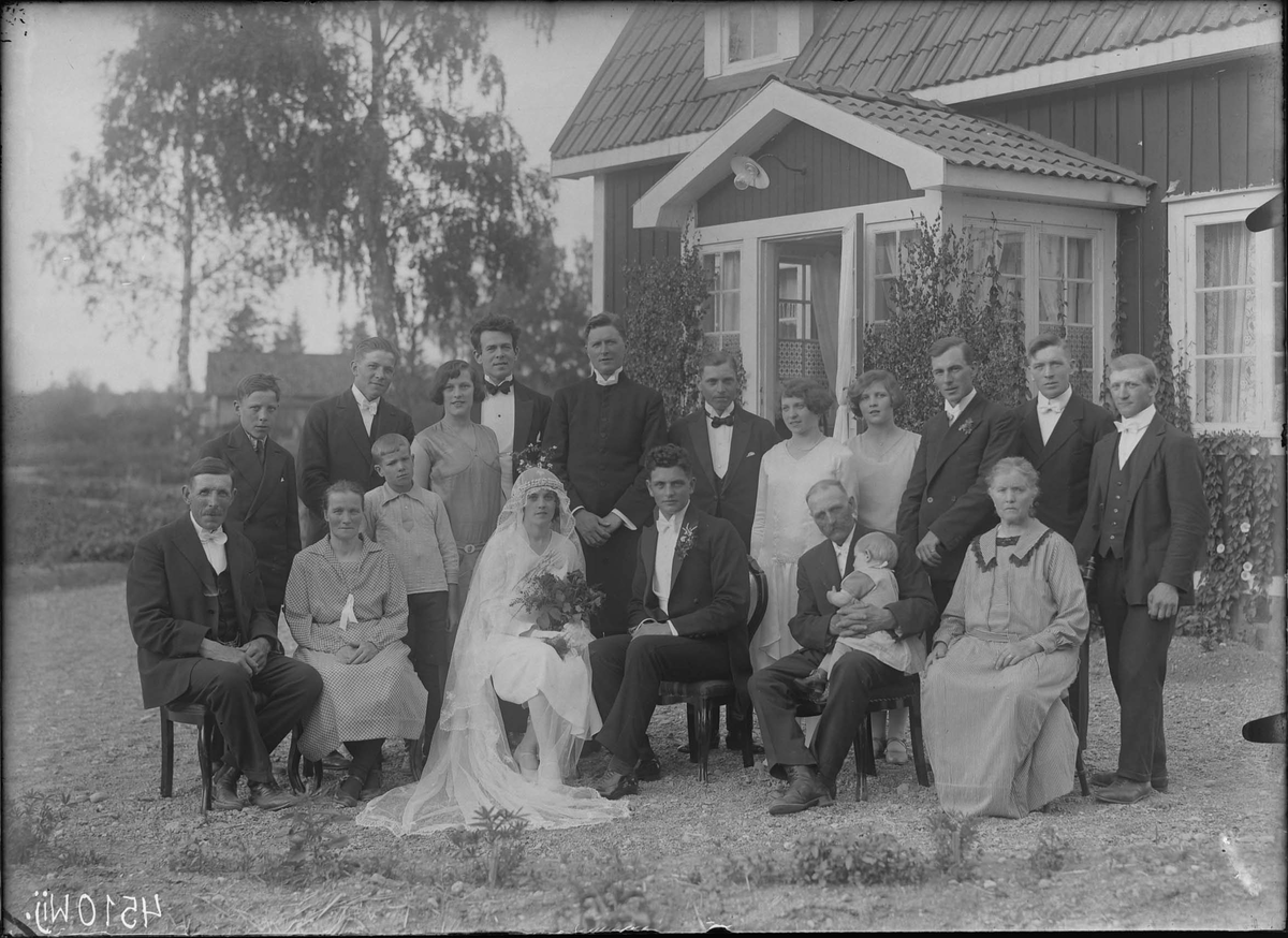 Fotografering beställd av Axel Karlsson. Föreställer sannolikt brudparet Axel Karlsson (1905-1951) och hans hustru Svea Eugenia Andersson (1904-1991) som gifte sig den 14 juli 1929. De omges av bröllopsgästerna.
