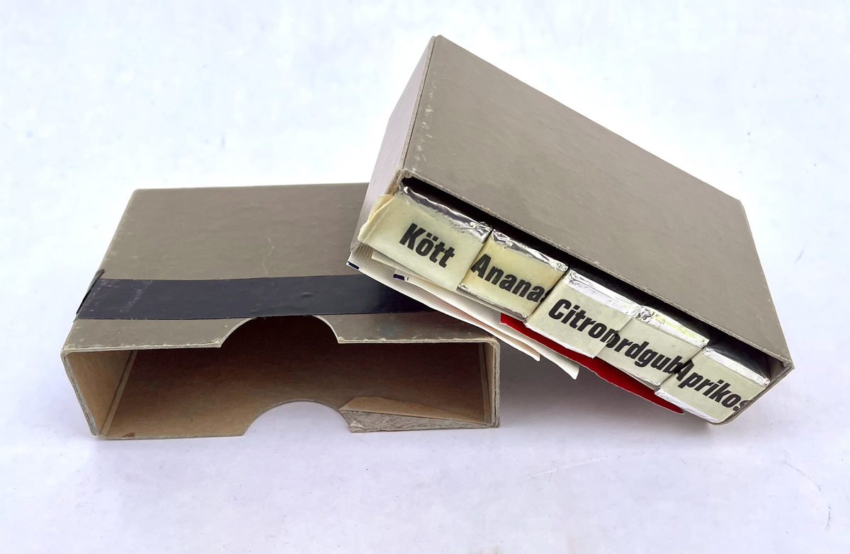 En nödportion i en olivgrön kartong med måtten 115 x 80 x 35 mm som består av två halvor – en ytterdel och en innerdel. Kartongen har ett varv svart el-tape runt ytterdelen. 
Kartongen innehåller en bruksanvisning, en stång med åtta bitar torkat rökt kött, fyra stänger med vardera åtta bitar fruktkarameller (ananas, citron, jordgubbe och aprikos), en portion snabbkaffe (cafe Salvador ”espresso” type), en tepåse, (Tetley) samt två 6,5g portionsförpackningar strösocker (Sockerbolaget).

Bruksanvisningens framsida har texten:
”NÖDPORTION ca 1000 kcal
Innehåll:
4 st. stänger á 8 bitar fruktkarameller
1 st. stång med 8 bitar torkat rökt kött
1 port fp kaffe
1 port fp te
2 port fp strösocker

Näringsvärde:
153 g kolhydrater (huvudsakligen i fruktkaramellerna)
20 g protein (huvudsakligen i köttstången)
32 g fett (ca hälften i karamellerna och hälften i köttstången)
Bruksanvisning:
Nödportionens sammansättning är från näringsfysiologisk synpunkt sådan, att prestationsförmågan bibehålles, om portionen äts enligt omstående anvisningar”

Bruksanvisningens baksida har texten:
”1. Nödportionen skall fördelas på flera mindre måltider (minst 8 st).
2. Fruktkarameller och köttbitar skall ätas omväxlande
(Proteininnehållet härrör nästan uteslutande från köttkomponenten och kolhydratinnehållet från fruktkomponenterna.)
Anm.
Nödportionen förorsakar ej onormal törst; ett vätskeintag om 1 l/dygn är tillräckligt (förutom i situationer där stark svettning uppträder).
BLÅ BAND PRODUKTER AB, HALMSTAD
TILLVERKAD jan 1972”