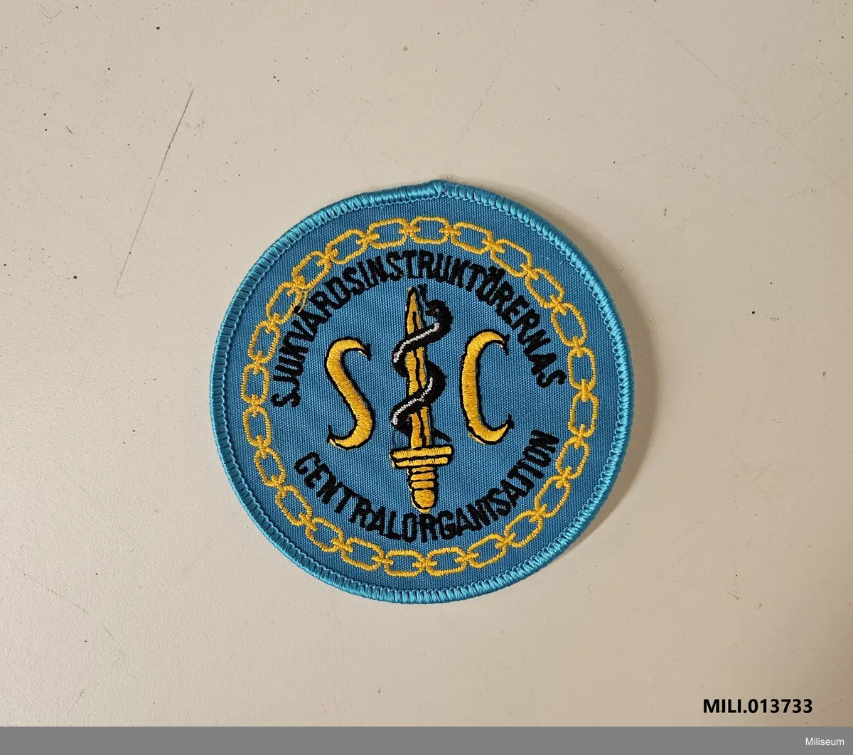 Tilläggstecken av textil med maskinbroderat motiv, avsett att sys fast på fältuniformens högra överärm (sannolikt).