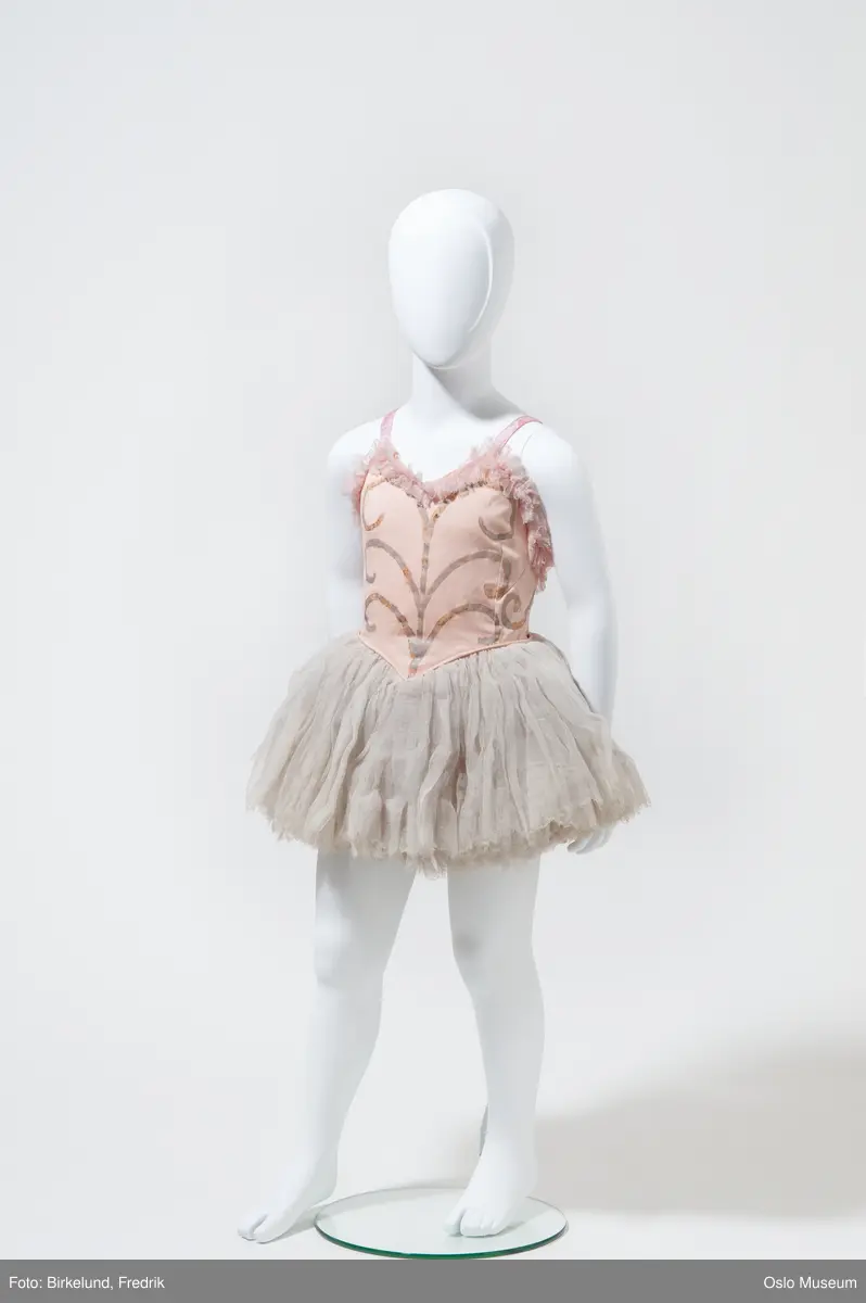 Ballettkjoler, barnestørrelse 8 stykk med liv av rosa bomullstoff med påmalt mønster i sølvfarge, rosa tyllkant og silkestropper.
Kort skjørt i hvit tyll i mange lag

