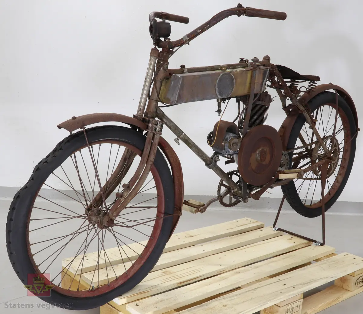 Motorsykkel med sort ramme og røde skjermer. Den har en enkel oppbygning som en motorisert tråsykkel med pedaler. Motor er en ensylindret firetaktsmotor, trolig en 120cc på 2  1/2 hk.
Motor er merket Lamaudiere no 528.
Opprinnelig var motorsykkelen levert med reimdrift, men har fått påbygd girkasse og kjededrift.
Bærer preg av lang tids lagring og har mye overflaterust. Motor og en del andre bevegelige deler sitter fastrustet.