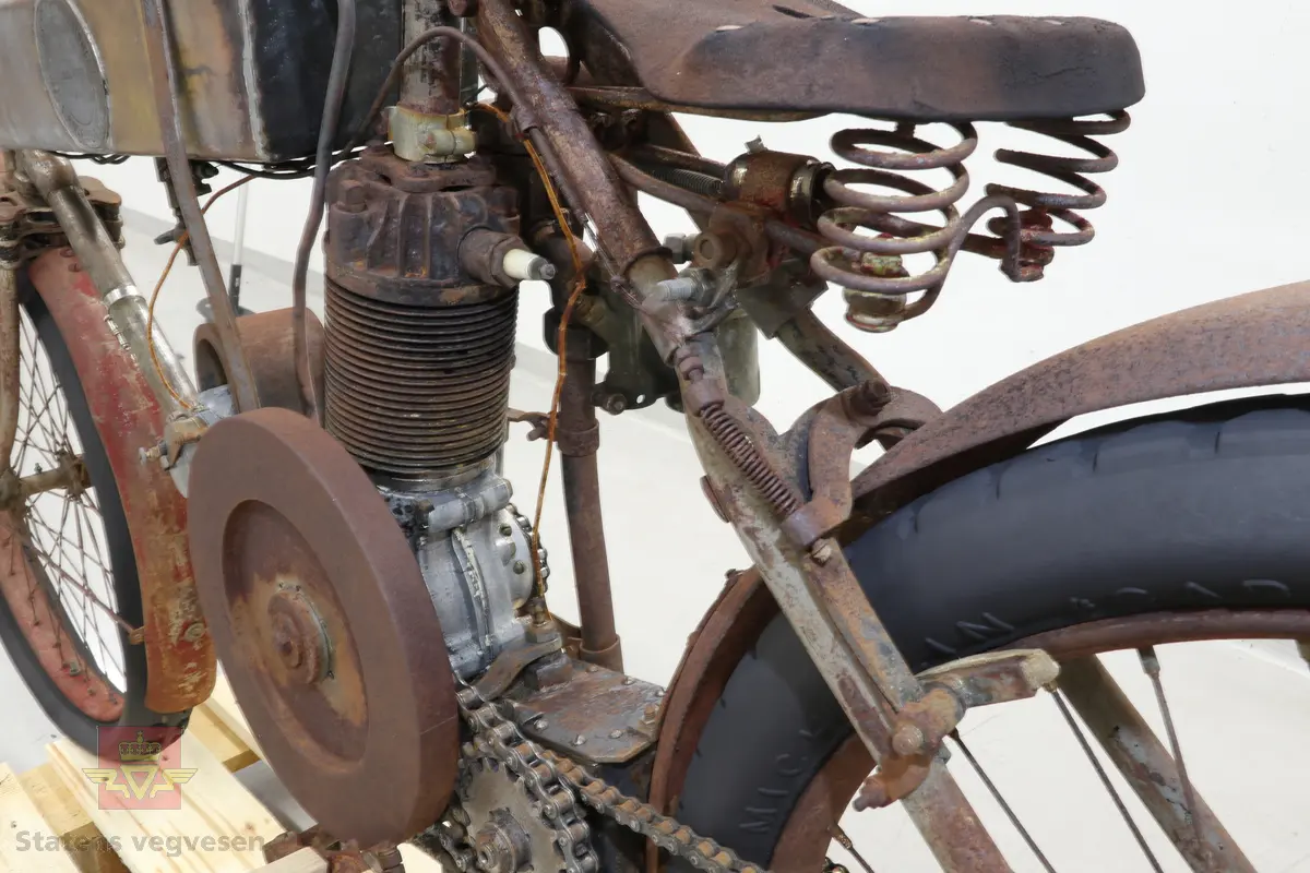 Motorsykkel med sort ramme og røde skjermer. Den har en enkel oppbygning som en motorisert tråsykkel med pedaler. Motor er en ensylindret firetaktsmotor, trolig en 120cc på 2  1/2 hk.
Motor er merket Lamaudiere no 528.
Opprinnelig var motorsykkelen levert med reimdrift, men har fått påbygd girkasse og kjededrift.
Bærer preg av lang tids lagring og har mye overflaterust. Motor og en del andre bevegelige deler sitter fastrustet.