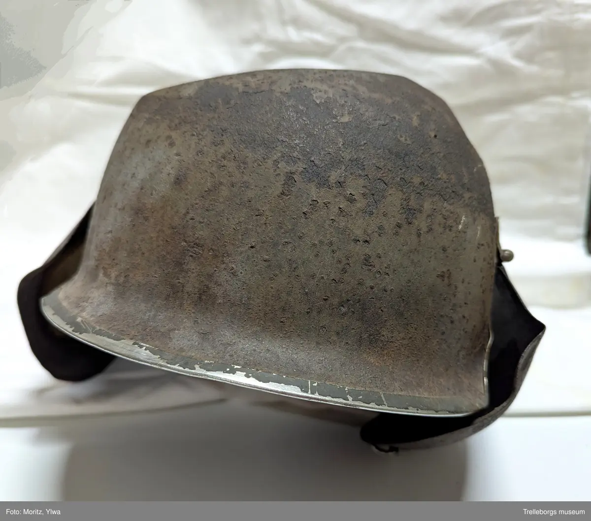 Gammal militär stålhjälm. Metallskydd fälls ner över öronen med gångjärn.