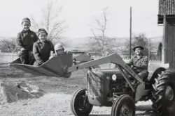 3 barn sittende i skuffa på en traktor. Per-Otto Landfald, T