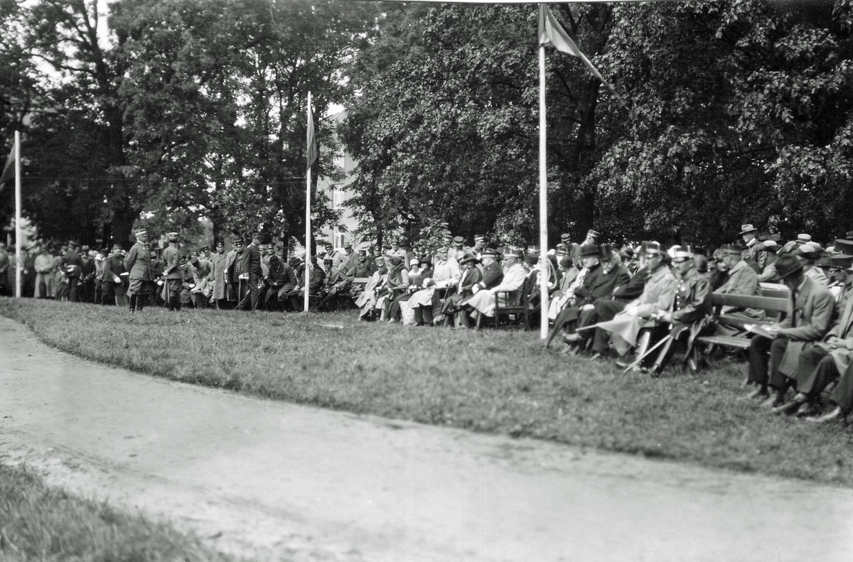 Västgöta regemente 1927. Ceremoni i regementsparken. Prins Carl i ljus kappa mitt emellan flaggstängerna.
