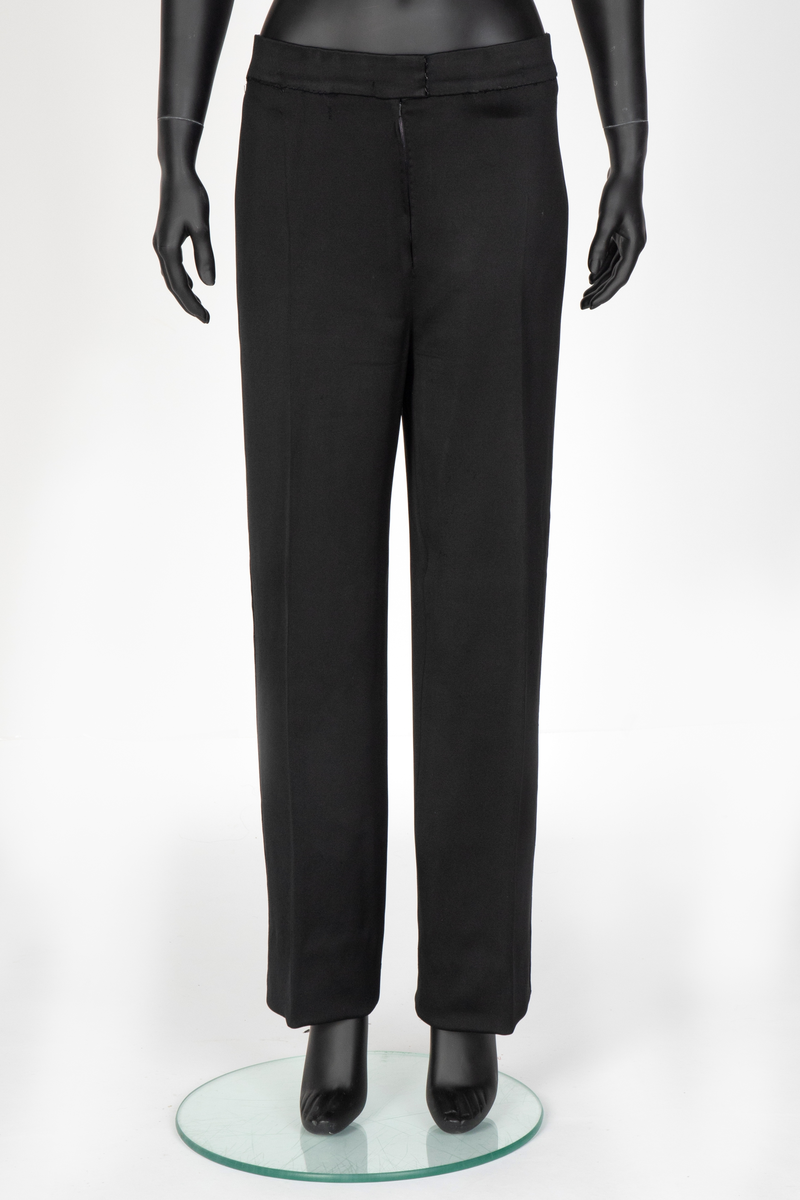 Smoking i svart silke- og ullsateng. Jakken har speilfløyelsslag og galloner. Enkeltspent med to knapper og tre lommer. Buksen har rette ben. Den er sydd ut i livet og linningen skjøtet på midt bak. Har hatt legg eller innsnitt foran. Tynn stripe i fløyel på siden av hvert bein.