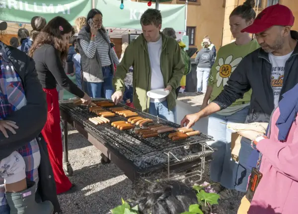 Besøkende griller pølser på kullgrill under Sankthansfeiring på Bogstad Gård.