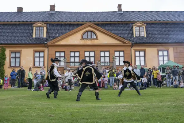 Tre fektere i kostymer opptrer foran publikum på plenen ved Bogstad Gård under Sankthansfeiring.