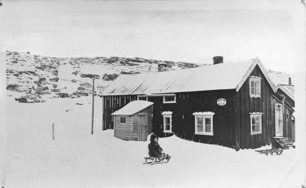 Landstadgården på Måsøy. 
Bildet er tatt i 1919, og viser Arne Ingebrigtsen (f.1917) utenfor Landstadgården på Måsøy i 1919. På tiden da bildet ble tatt var 1.etasje mot nord brukt som vaskeri. Før dette var dette kjøkkenet. Stua mot sør (mot venstre). 
På veggskiltet står Telegrafstation - Rikstelefon. Måneskaren (drengen) bodde på loftet mot nord. Tilbygget bak med trappetrinn opp til stabburet. Helt til høyre er stasjonen.