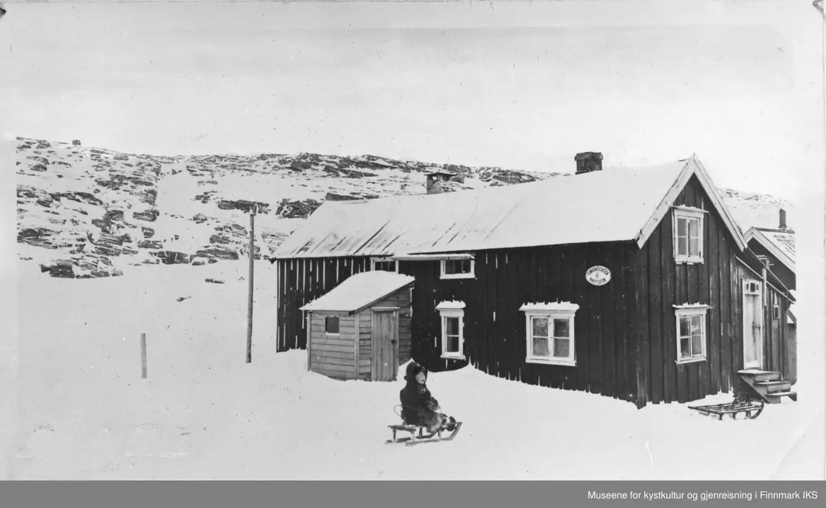 Landstadgården på Måsøy. 
Bildet er tatt i 1919, og viser Arne Ingebrigtsen (f.1917) utenfor Landstadgården på Måsøy i 1919. På tiden da bildet ble tatt var 1.etasje mot nord brukt som vaskeri. Før dette var dette kjøkkenet. Stua mot sør (mot venstre). 
På veggskiltet står Telegrafstation - Rikstelefon. Måneskaren (drengen) bodde på loftet mot nord. Tilbygget bak med trappetrinn opp til stabburet. Helt til høyre er stasjonen.