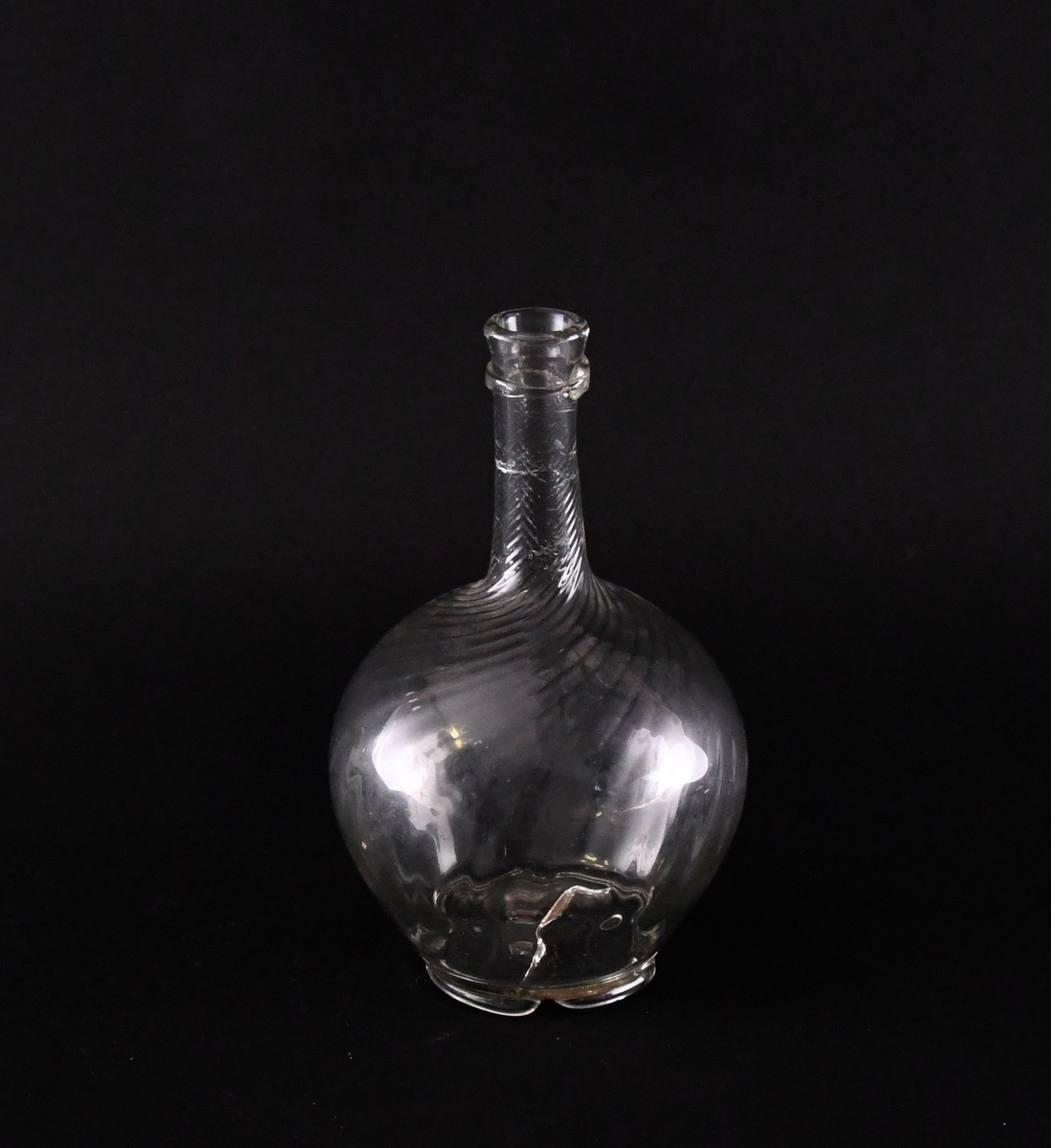 Karaffel av håndblåst glass. Kuleformet korpus, med lang og tynn hals. Karaffelen har bølgeformet fotring. Karaffelen har spiralisert dekor. Karaffelen har krage under helletuten.
