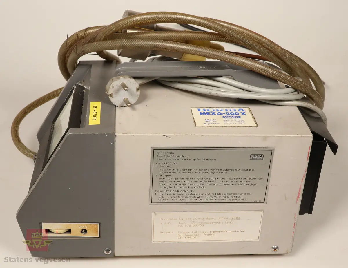 En avgassmåler for bensinmotorer av første generasjon. Innkapslet i plast, grå og svart. Har skala som viser Coprosenten. Grå 220 volt enfaskabel tilkoblet. Har 3,5 meter lang plastslange med vannfilter og føler tilkoblet. Føleren stikkes i eksosrøret. Målerne skal være helt i orden i følge giver. 