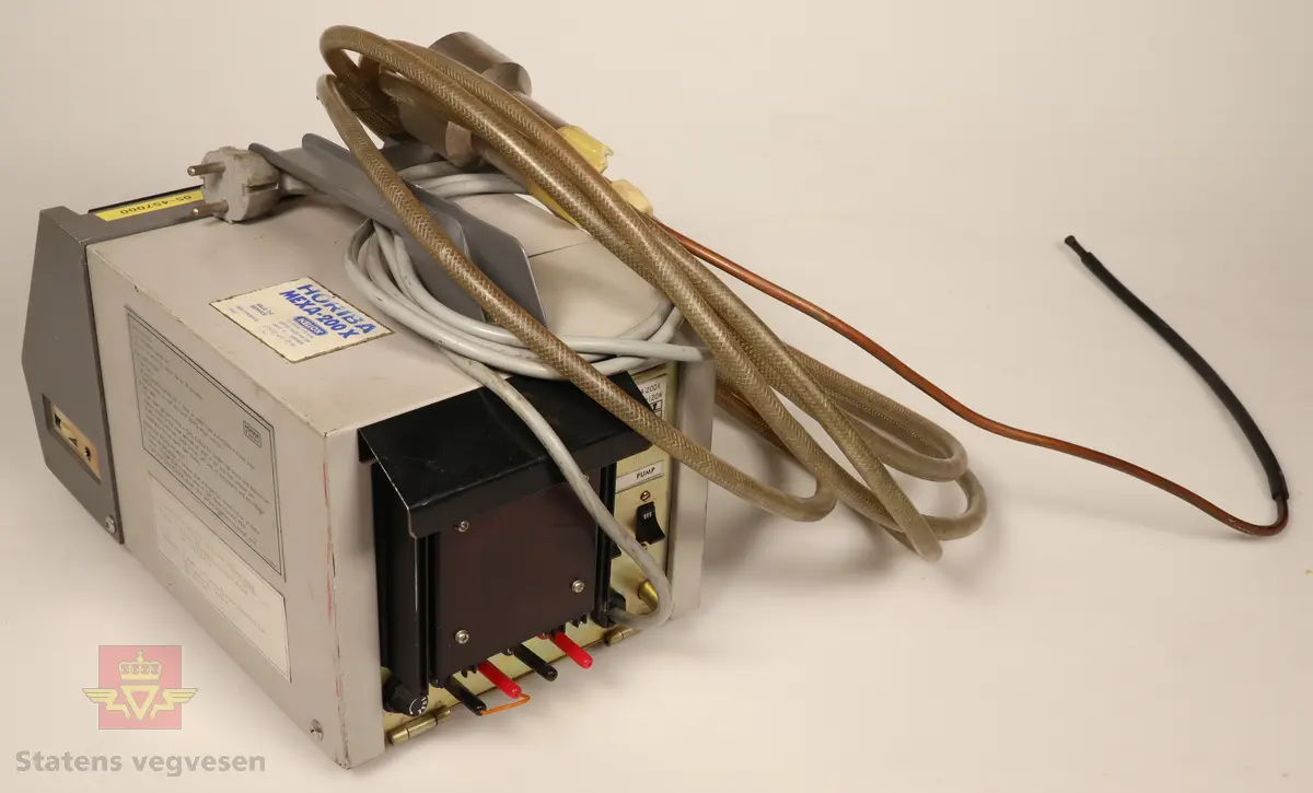 En avgassmåler for bensinmotorer av første generasjon. Innkapslet i plast, grå og svart. Har skala som viser Coprosenten. Grå 220 volt enfaskabel tilkoblet. Har 3,5 meter lang plastslange med vannfilter og føler tilkoblet. Føleren stikkes i eksosrøret. Målerne skal være helt i orden i følge giver. 