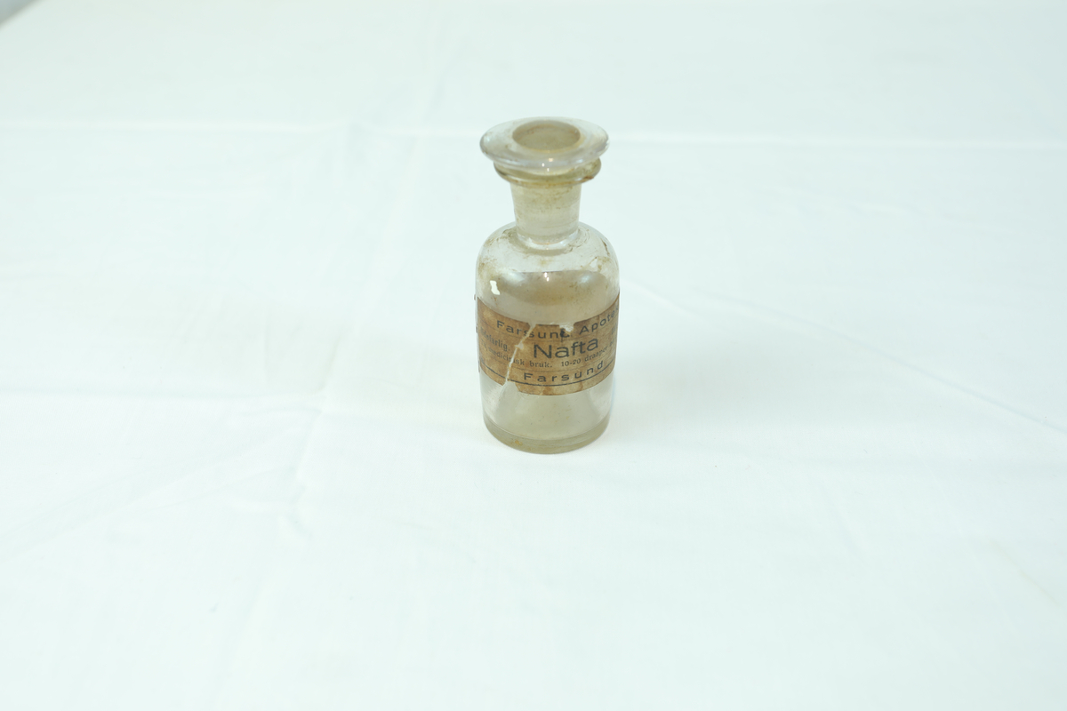 Medisinflaske med glasslokk. Har vært brukt til oppbevaring av medisin.