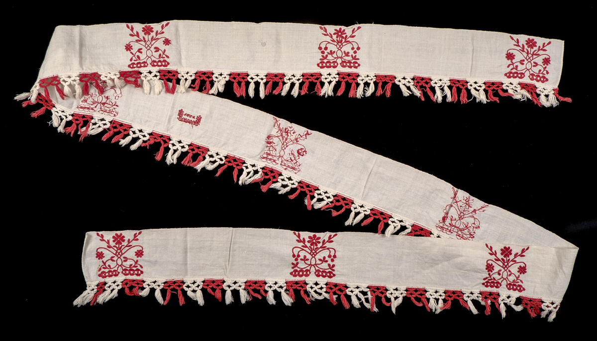 Hängkläde i vit lärft (bomull?), dekorerat med broderi i hallandssöm med rödfärgad bomullstråd. Broderierna består av två omväxlande mönsterpartier som upprepas sammanlagt nio gånger längs klädets längd – det ena mönstret fyra gånger, det andra två gånger. Strax till höger om mittpartiet finns ett monogram i korsstygn: "ABND" (troligtvis Anna Brita Nilsdotter). Hängklädet är tillverkat i ett stycke. Längs den nedre kanten löper en bård med knuten frans – varannan knut röd och varannan vit.