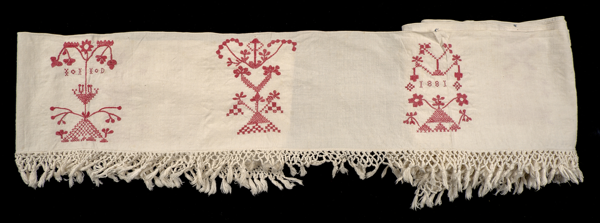Hängkläde i vit bomullslärft, dekorerat med broderi i hallandssöm med rödfärgad bomullstråd. Broderierna utgörs av sammanlagt femton unika motivpartier, placerade längs klädets längd. I det fjärde motivpartiet från höger samt det andra från vänster finns monogram med ej identifierade initialier: "IL ID"?. I det fjärde motivpartiet från vänster återfinns årtalet 1881.

Motivpartierna är placerade med ojämna mellanrum längs textilen. Broderierna uppvisar variation i utförande. Tygstycket är oregelbundet klippt och fållat.