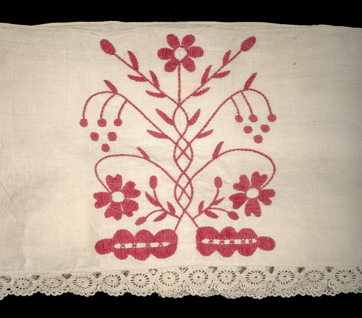 Hängkläde i vit linnelärft, dekorerat med broderi i hallandssöm med rödfärgad bomullstråd. Broderierna utgörs av två omväxlande mönsterpartier som upprepas sammanlagt tio gånger längs klädets längd. På klädets högra sida två uppsättningar monogram i korsstygn: "AC ND", samt årtalet 1869. Hängklädet är sammansatt av tre tygstycken. Samtliga kanter är fållade. Den nedre fållen är försedd med en knypplad bård i hjulformade mönster.