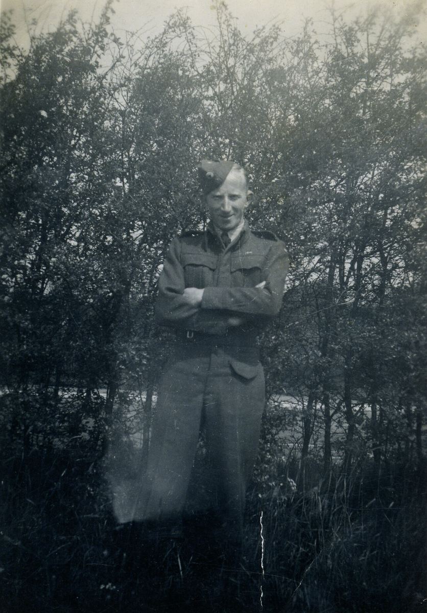 Håkon Telle frå Telavåg i uniform frå flyvåpenet. Buskar i bakgrunnen.