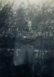 Håkon Telle frå Telavåg i uniform frå flyvåpenet. Buskar i bakgrunnen.