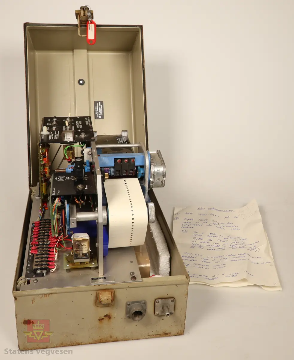 Trafikkteller montert i grå stålkasse med hengelås. I stålkassen ligger en bruksanvisning for Trafikkteller. Trafikktelleren drives av typen Varta spesial 431 (6V - IEC 4R25). Disse er nå utkoblet og ligger i kassa. Tellerens serienummer er 2704.
Følgende utstyr hører til trafikktelleren:

NVM 02909 - 001 Håndskrevet bruksanvisning til trafikkteller. 2 sider. Blå skrift.
NVM 02909 - 002 Hvit papirrull, ubrukt. Til skriveren på trafikktelleren.
NVM 02909 - 003 Svart gummislange. Brukt som føler til trafikkteller. 
NVM 02909 - 004 Svart gummislange. Brukt som føler til trafikkteller. 
NVM 02909 - 005 Svart gummislange. Brukt som føler til trafikkteller. 
NVM 02909 - 006 Svart gummislange. Brukt som føler til trafikkteller. 
NVM 02909 - 007 Svart gummislange. Brukt som føler til trafikkteller. 
NVM 02909 - 008 Svart gummislange. Brukt som føler til trafikkteller. 
NVM 02909 - 009 Svart gummislange. Brukt som føler til trafikkteller. 
NVM 02909 - 010 Svart gummislange. Brukt som føler til trafikkteller. 
NVM 02909 - 011 Svart gummislange. Brukt som føler til trafikkteller. 
NVM 02909 - 012 Svart gummislange. Brukt som føler til trafikkteller. 
NVM 02909 - 013 Svart gummislange, med festplate og endestykke. Ca. 10 meter lang. Dette er den mest komplette føleren som er med telleapparatet. 
NVM 02909 - 014 Stålspiker. Brukt til å slå fast festplaten med føler i vegbanen. 
NVM 02909 - 015 Kjetting av galvanisert stål, ca. 4 m lang.
