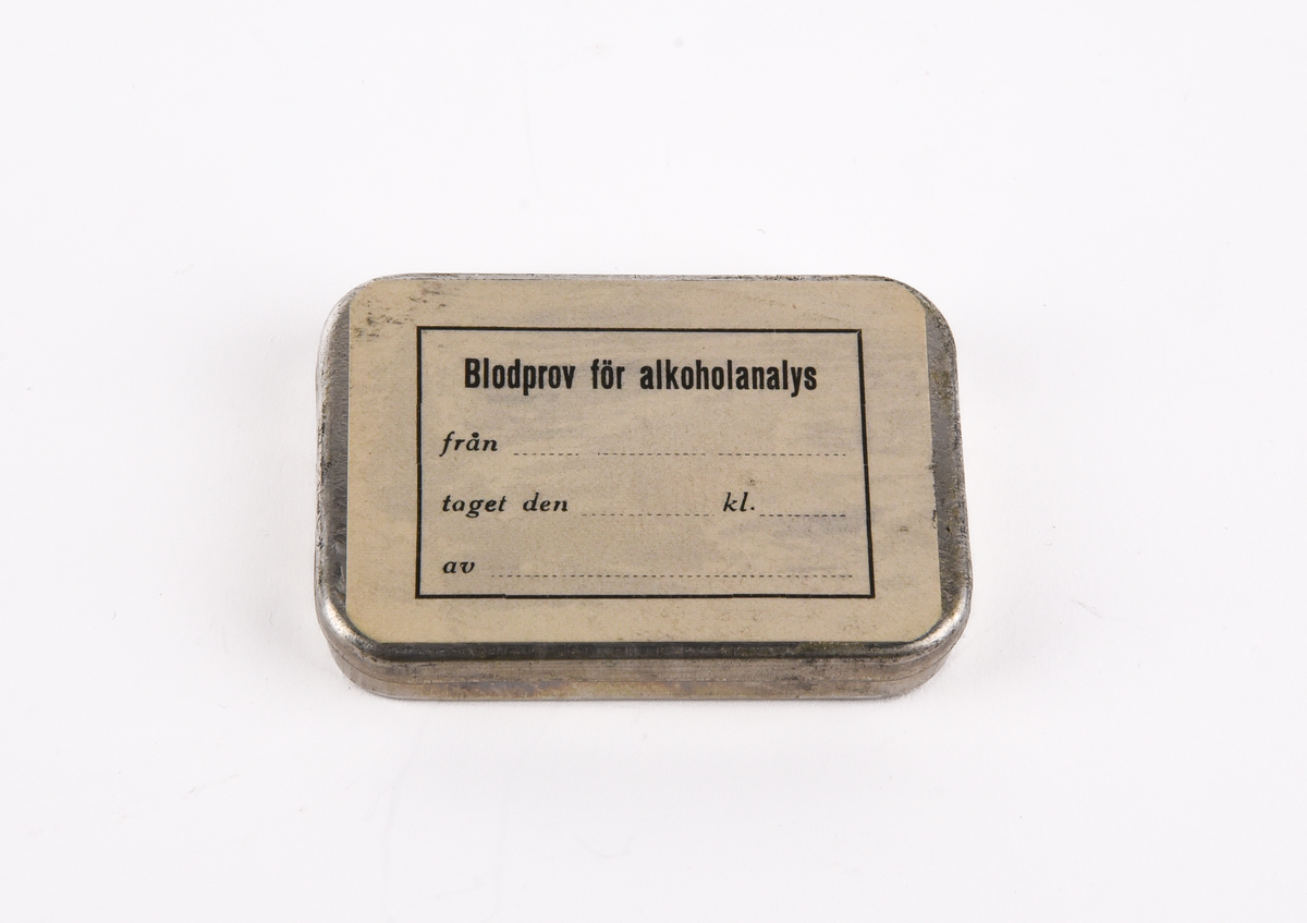 Kuvert med provtagningsset för blodprov för alkoholanalys med tillhörande protokoll.
Rektangulärt, brunt kuvert (:1) med text i svart som lyder "Express Till Statens Rättskemiska laboratorium Lindhagensg 126 Stockholm".
Protokoll (:2) som fylls i vid undersökningen. Rubriken lyder "Protokoll, fört vid undersökning för påvisande av alkoholpåverkan." Protokollet avslutas med en "Bruksanvisning vid tagandet av blodprov för alkoholbestämning.".
Ask i plåt (:3) med etikett på locket. Etikettens text i svart lyder "Blodprov för alkoholanalys från ... taget den ... kl. ... av ...". Asken innehåller bomull som skyddar tre glasrör och sex gummidetaljer.