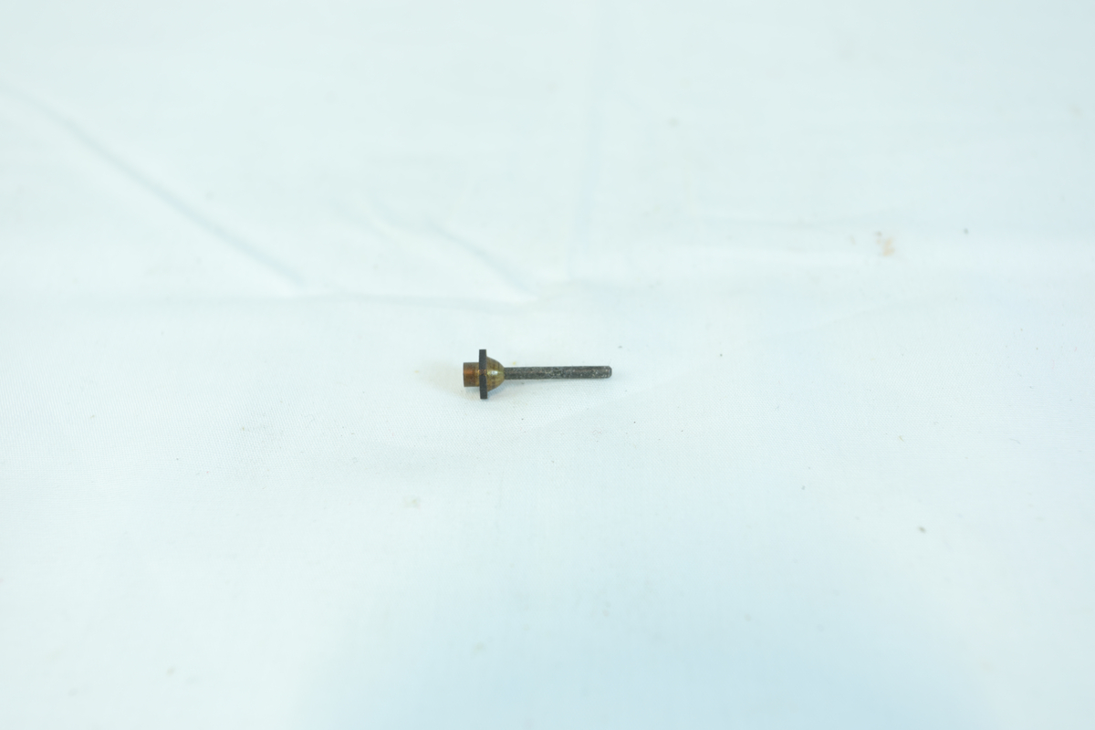 En liten metallgjenstand, sannsynligvis en skrue eller bolt med skive og mutterfeste.