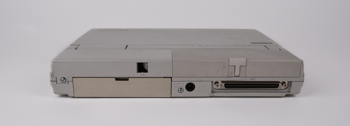 Bärbar dator (:1) Toshiba "T1000LE" av grå plast. Uppfällbar bildskärm som i uppfällt läge tillgängliggör tagentbordet med QWERTY-layout och svenska tecken. Löstagbar pappersremsa med kortkommandon ovanför tagentbordet. På sidan en port för 3,5-tums disketter. På baksidan en port till laddningsdocka (:2), även denna i grå plast. Laddningsdockan har ett flertal uttag till olika kablar, bland annat till en strömadapter (:3) i svart plast med tillhörande kabel. 
Två tillhörande 3,5-tums disketter (:4-5) även dessa från Toshiba. Med operativsystemet MS-DOS 3.3. Fyra tillhörande användarmanualer (:6-9). En manual med allmän information för den bärbara datorn på svenska. En manual för MS-DOS 3.3, en för den bärbara datorn och en för laddningsdockan, samtliga på engelska.