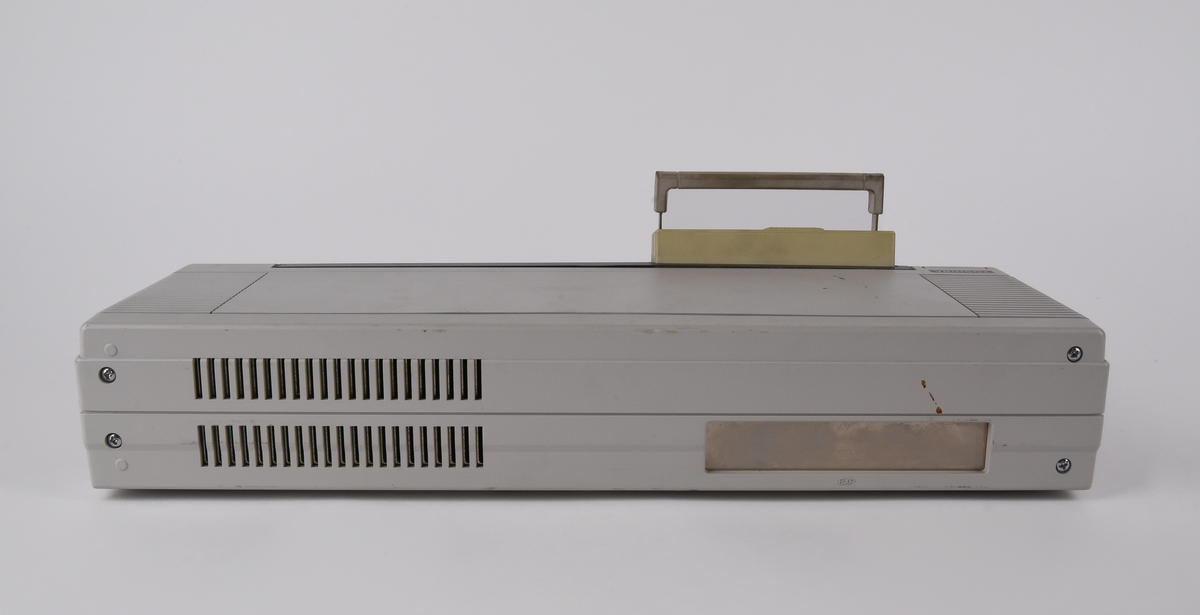 Bärbar dator (:1) Toshiba "T1000LE" av grå plast. Uppfällbar bildskärm som i uppfällt läge tillgängliggör tagentbordet med QWERTY-layout och svenska tecken. Löstagbar pappersremsa med kortkommandon ovanför tagentbordet. På sidan en port för 3,5-tums disketter. På baksidan en port till laddningsdocka (:2), även denna i grå plast. Laddningsdockan har ett flertal uttag till olika kablar, bland annat till en strömadapter (:3) i svart plast med tillhörande kabel. 
Två tillhörande 3,5-tums disketter (:4-5) även dessa från Toshiba. Med operativsystemet MS-DOS 3.3. Fyra tillhörande användarmanualer (:6-9). En manual med allmän information för den bärbara datorn på svenska. En manual för MS-DOS 3.3, en för den bärbara datorn och en för laddningsdockan, samtliga på engelska.