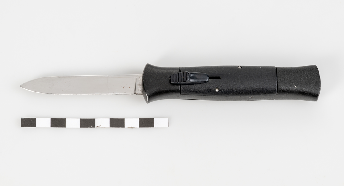 Stilettkniv. Knivblad i bajonettstil som frigörs framåt med skjutknappssystem. Svart knivskaft.