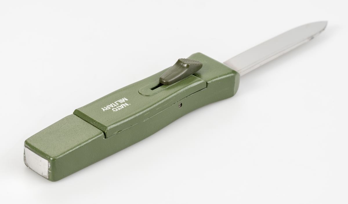 Stilettkniv. Knivblad i bajonettstil som frigörs framåt med skjutknappssystem. Militärgrönt knivskaft.