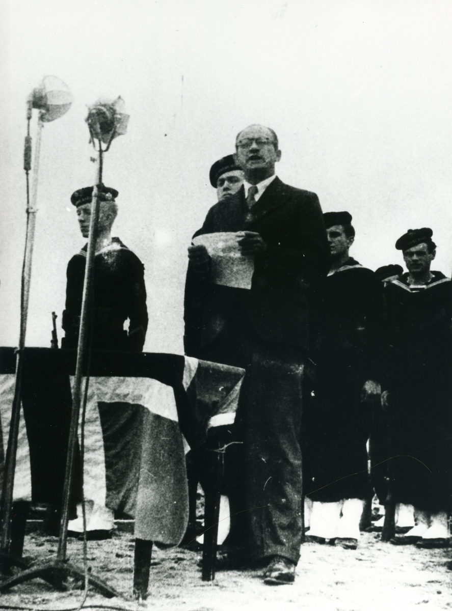 Ein av talarane 21.08.1949 då minnesteinen i Telavåg over dei falne under andre verdskrigen vart avduka. Marinegastar i bakgrunnen og mikrofonar er sett opp.